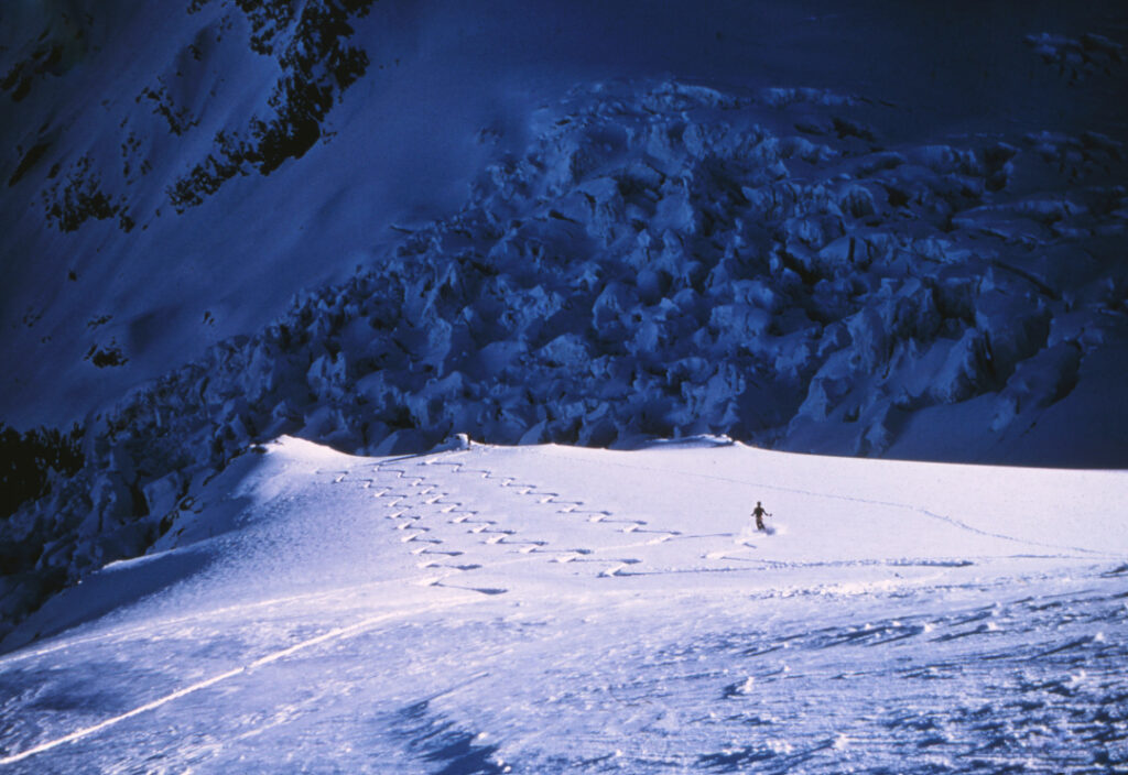 A scanned colour slide of skier laying tracks down from Plateau hut with the Hochstetter icefall in the background. 1976 Mt Cook National Park, New Zealand